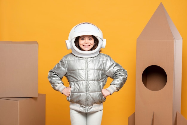 Ragazza con casco spaziale e nave fatta di cartone