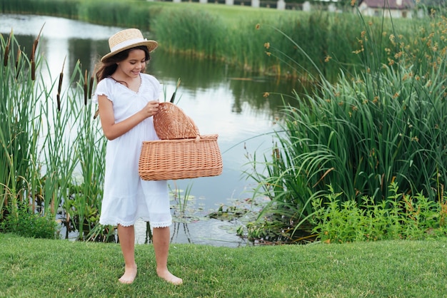 Ragazza con cestino da picnic in riva al lago