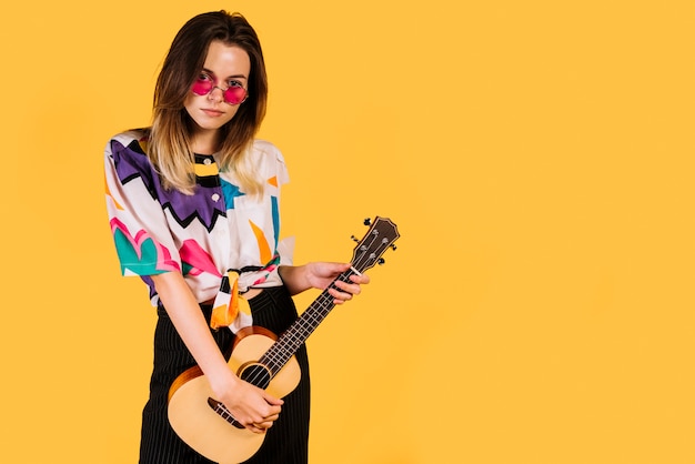 Ragazza con gli occhiali a suonare il ukelele