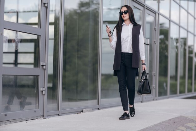 Ragazza con gli occhiali da sole guardando il suo smartphone