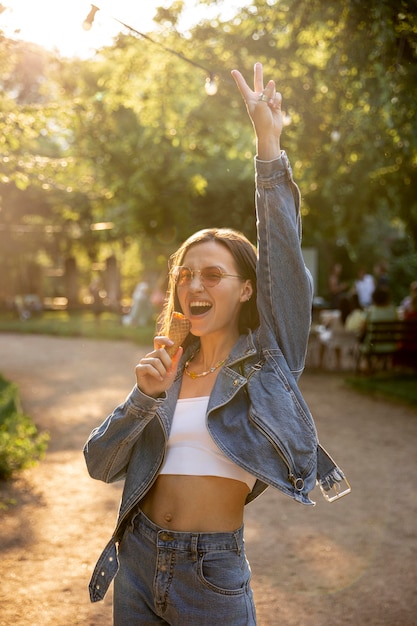 Ragazza con gli occhiali da sole in parco che mangia il gelato