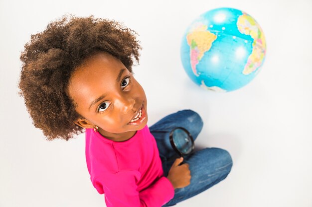 Ragazza con globo e lente di ingrandimento in studio