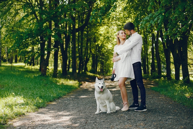 ragazza con i capelli chiari e un vestito bianco sta camminando in una foresta assolato con il suo fidanzato