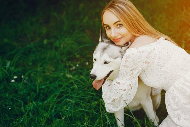 ragazza con i capelli chiari vestita in abito bianco sta giocando con il suo cane