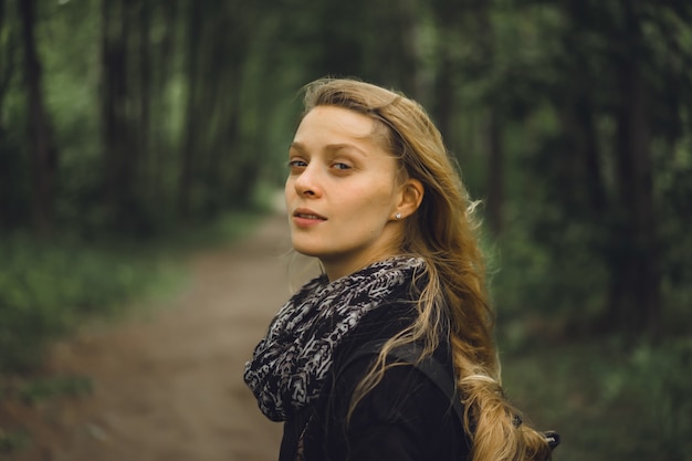 ragazza con i capelli lunghi cammina attraverso la foresta.