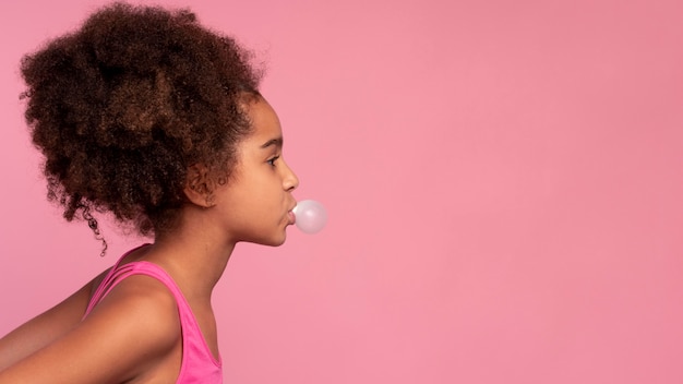 Ragazza con i capelli ricci che fa una gomma da masticare