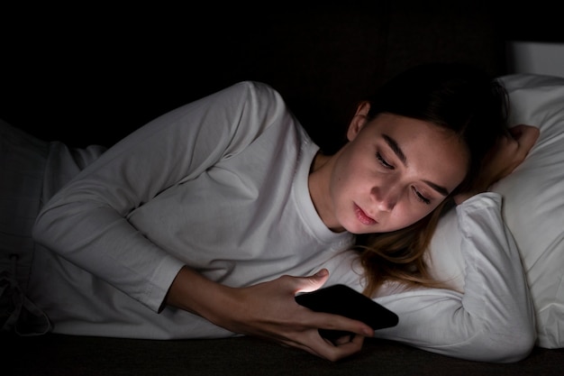 Ragazza con il cellulare a letto