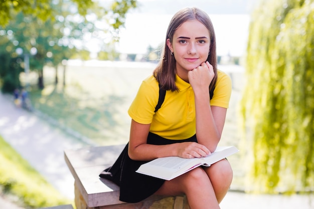 Ragazza con il libro guardando la fotocamera