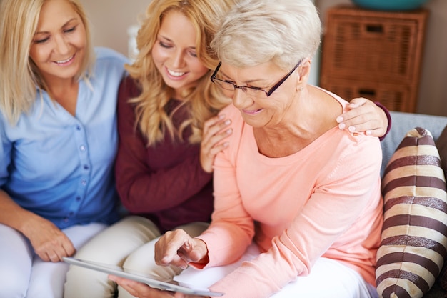 Ragazza con la mamma che sostiene la nonna che imparare usa la tavoletta digitale