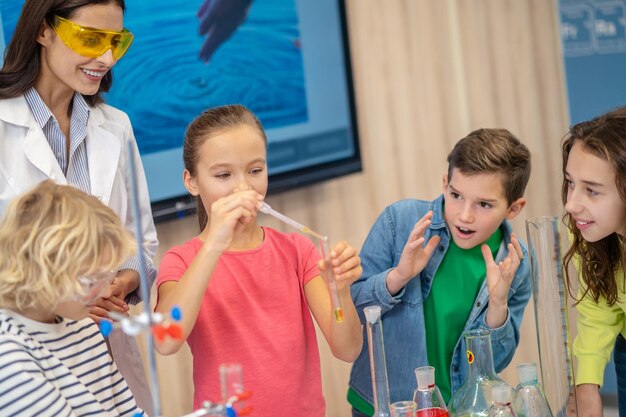 Ragazza con la provetta e guardare i bambini con l'insegnante