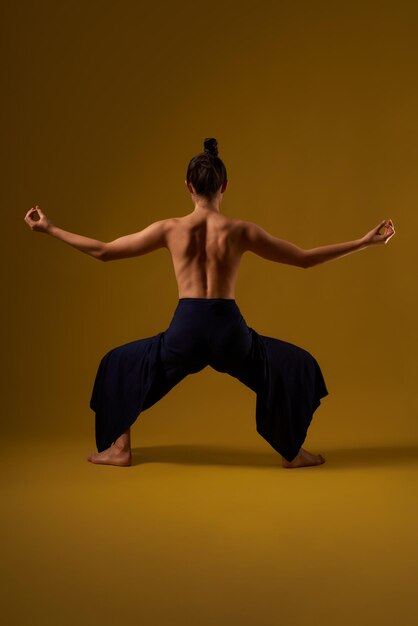 Ragazza con la schiena nuda che pratica la posa di yoga