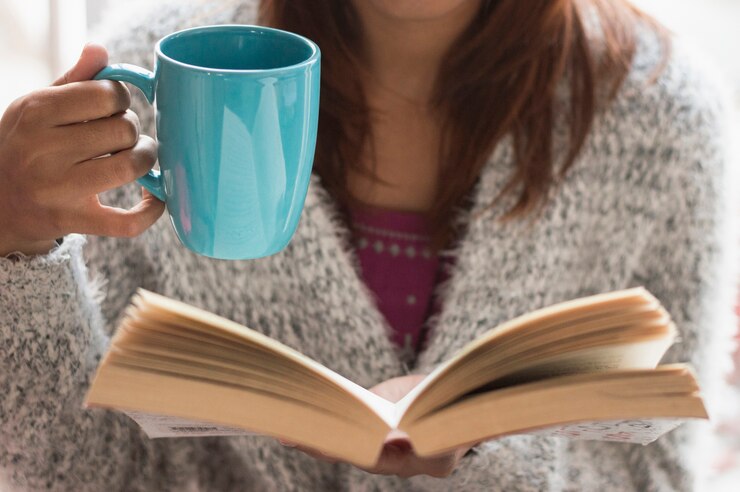 Foto gratuito ragazza con la tazza e libro aperto