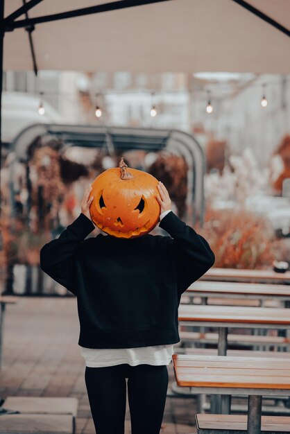 Ragazza con la testa di zucca in posa per strada