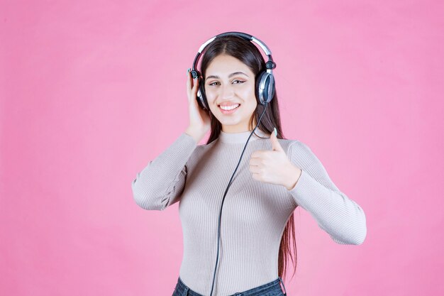 Ragazza con le cuffie che ascolta la musica e mostra il suo divertimento