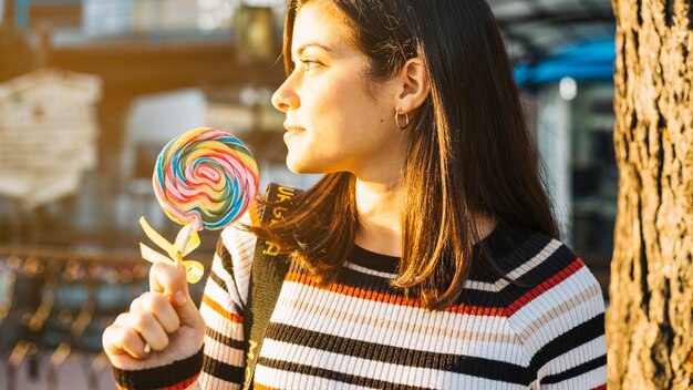 Ragazza con lecca-lecca colorata illuminata dal sole