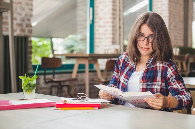 Ragazza con libro in posa in caffè