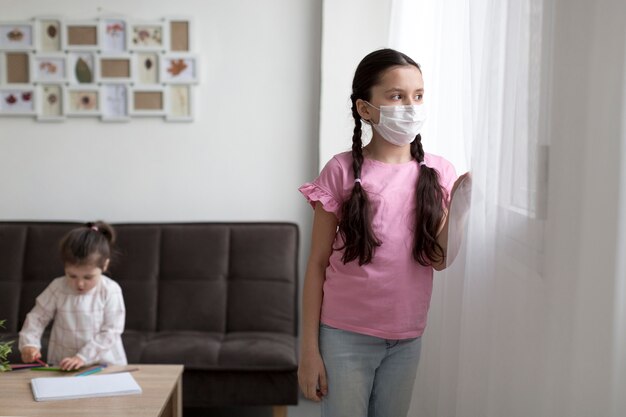 Ragazza con maschera guardando fuori dalla finestra