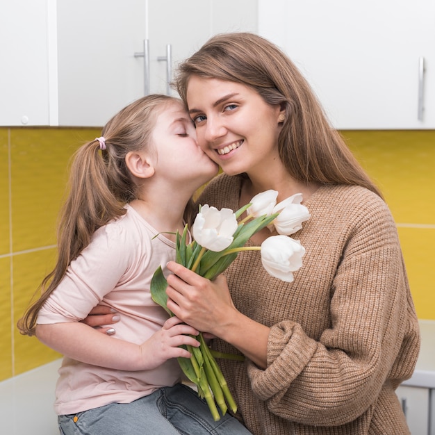 Ragazza con tulipani bacia la madre sulla guancia