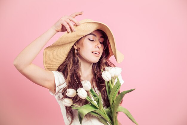 ragazza con un cappello e tulipani su uno sfondo colorato