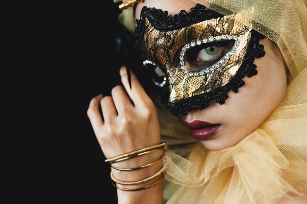Ragazza con un ornamento di colore giallo sulla testa e una maschera veneziana