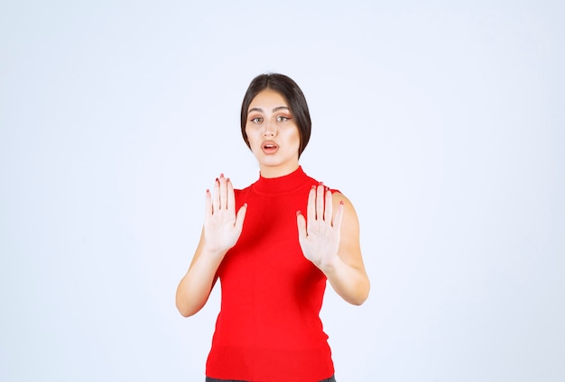 Ragazza con una camicia rossa che ferma qualcosa con le mani.