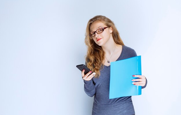 Ragazza con una cartella blu che controlla i suoi messaggi.