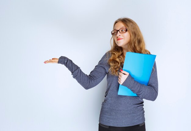 Ragazza con una cartella blu che punta al suo collega.