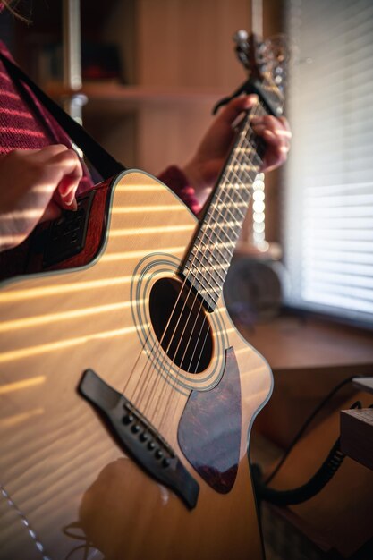 Ragazza con una chitarra alla luce del sole attraverso le persiane