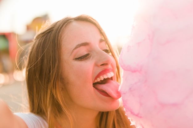 Ragazza con zucchero filato nel parco di divertimenti