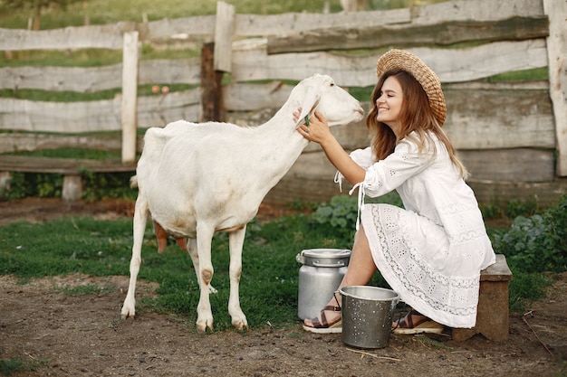 Ragazza contadina con capra bianca. Donna e piccola capra erba verde. Fattoria ecologica. Concetto di fattoria e allevamento. Animali del villaggio.