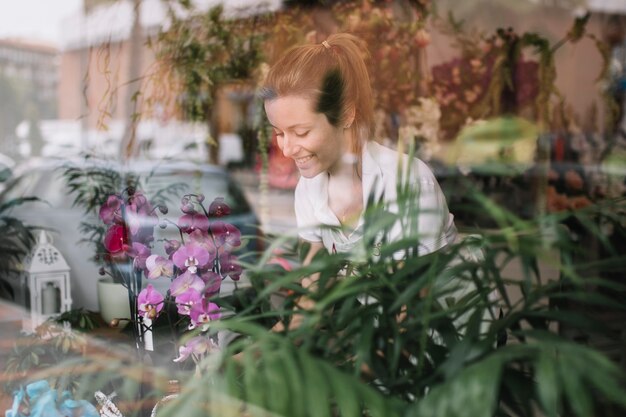 Ragazza contenta che lavora con i fiori in negozio