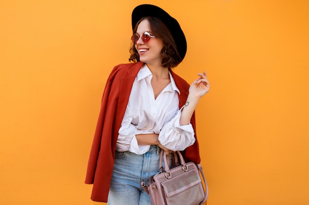 Ragazza dai capelli corti sorridente felice che posa sopra la parete gialla. Colori caldi. umore positivo.