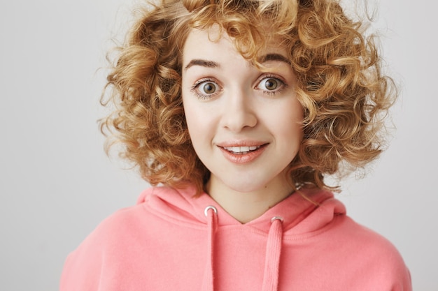 Ragazza dai capelli ricci carina sorpresa che sembra divertita