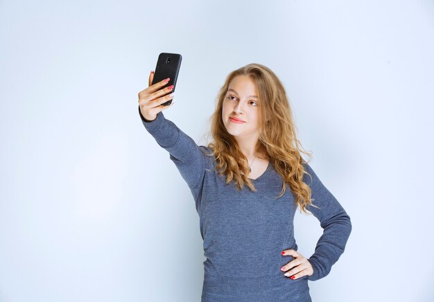 Ragazza dai capelli riccia bionda che prende il suo selfie