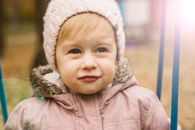 Ragazza del bambino soleggiata in cappello lavorato a maglia, guardando avanti