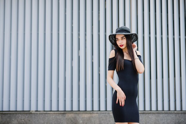 Ragazza del brunette che si leva in piedi contro le persiane