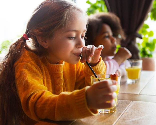 Ragazza del colpo medio che beve succo