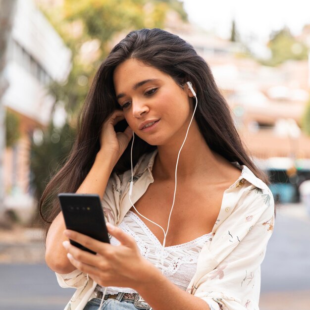 Ragazza del colpo medio che esamina telefono