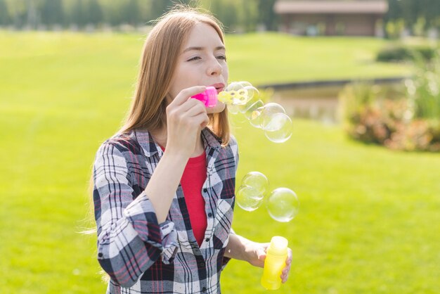 Ragazza del colpo medio che fa le bolle di sapone