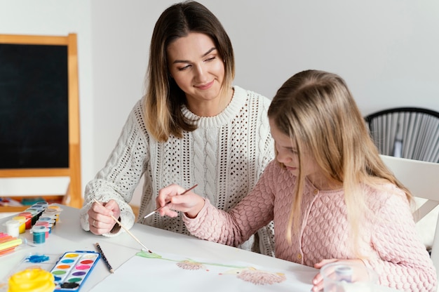 Ragazza del colpo medio che impara a dipingere