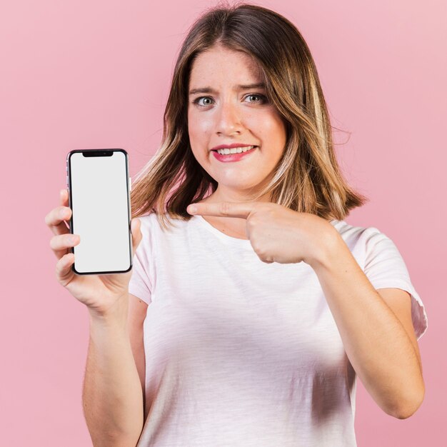 Ragazza del colpo medio che indica al telefono