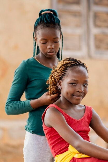 Ragazza del colpo medio che intreccia i capelli dell'amico