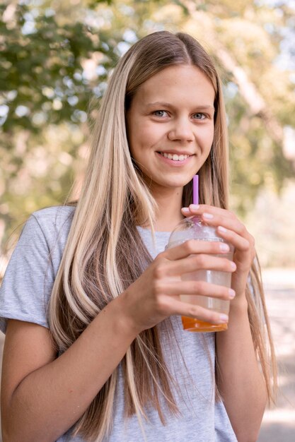 Ragazza del colpo medio che posa con la bevanda