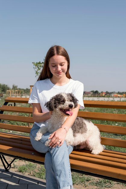 Ragazza del colpo medio con il cane sulla panchina