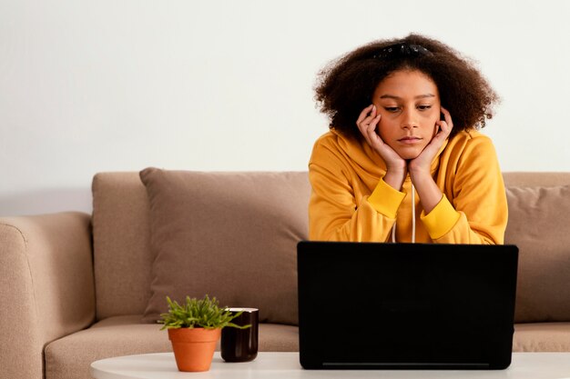 Ragazza del colpo medio con il computer portatile sul divano