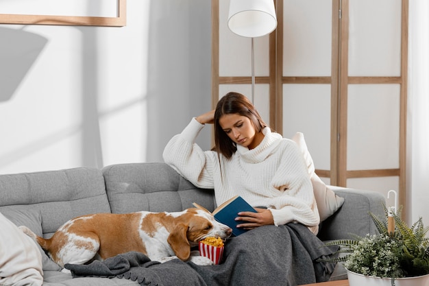 Ragazza del colpo medio sul divano con il cane