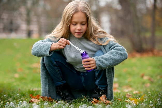 Ragazza del colpo pieno che fa le bolle di sapone