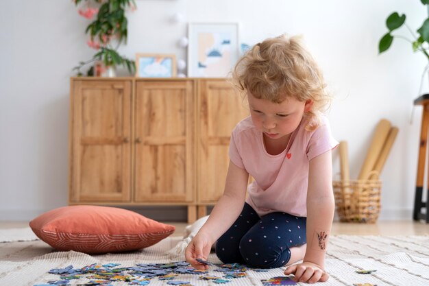 Ragazza del colpo pieno che fa puzzle sul pavimento