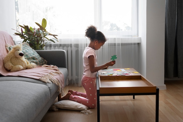 Ragazza del colpo pieno che fa puzzle sul tavolo