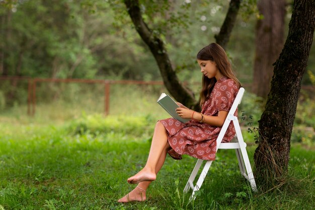 Ragazza del colpo pieno che legge in natura